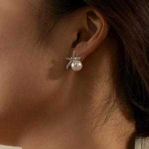 Close-up of S925 silver bow stud earrings with white pearl and sparkling zircon stones