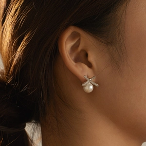 Elegant S925 sterling silver bow earrings with round white pearl and zircon accents on a model
