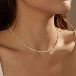 Macro detail of delicate 3mm small white pearl choker necklace on a female model
