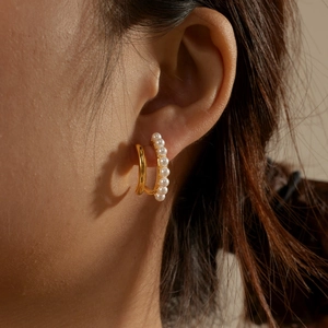 Close-up of elegant double-layered gold hoop earrings with small white pearls