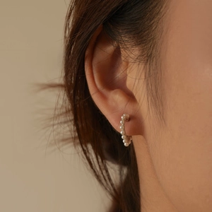 Close-up of elegant S925 sterling silver heart-shaped pearl hoop earrings worn by model