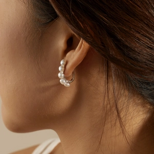 Macro detail of silver hoop earrings featuring five round white freshwater pearls
