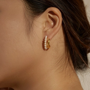 Macro detail of S925 silver earring with double-loop gold finish and inlaid white pearls