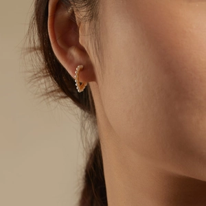 Close-up of S925 silver C-shaped earrings with pearls on a golden metal base