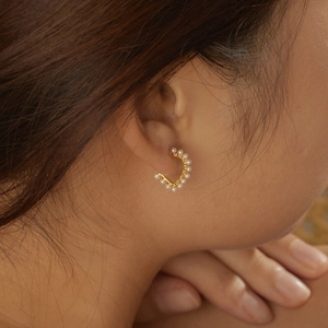 Elegant gold S925 silver C-shape earrings with delicate white pearls worn by a model