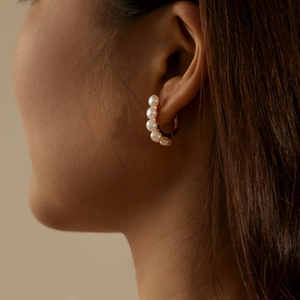Elegant gold C-shaped hoop earrings with five white freshwater pearls on female model
