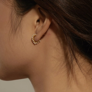 Close-up of gold hoop earrings with small white pearls on a model for daily wear