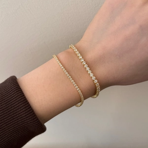 Close-up of dual gold tennis bracelets with sparkling round cubic zirconia on a wrist