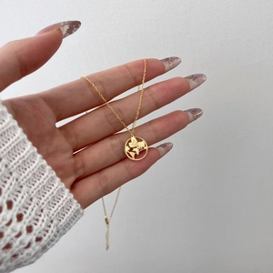 Macro shot of gold world map necklace pendant with heart engraving and just GO slogan