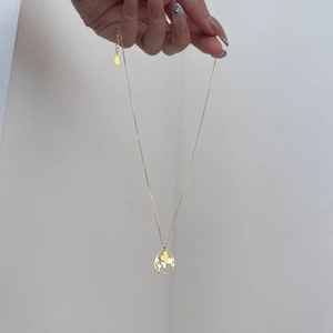 Detail of S925 sterling silver globe pendant with heart and Just GO engraving on gold chain