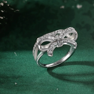 Macro shot of silver bow ring with sparkling zircons on a deep green festive background