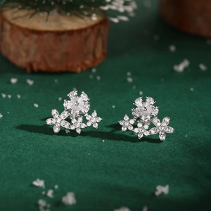 Detailed view of silver flower stud earrings with sparkling cubic zirconia on green velvet