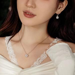 Détail de boucles d'oreilles et collier fleur en argent S925 avec zircons sur un modèle