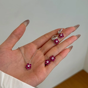 Détail du pendentif fleur magenta et boucles d'oreilles argentées du coffret bijoux