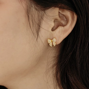 Close-up of elegant gold butterfly stud earring with sparkling zircon pavé on ear
