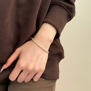 Detail of a gold-plated 925 sterling silver tennis bracelet worn on a female wrist