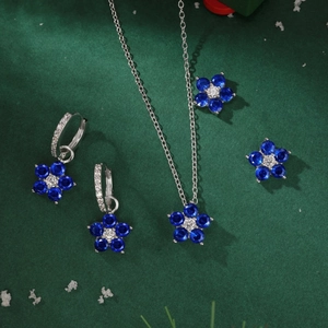 Détail de la parure bijoux fleurs de prunier bleues et cristaux sur fond de neige