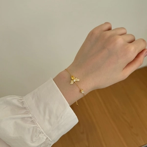Detailed shot of golden bee bracelet with cubic zirconia and honeycomb charm on wrist