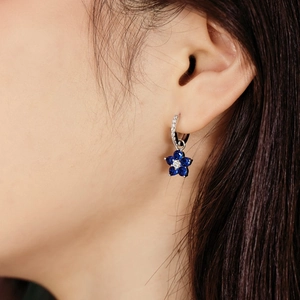 Détail de boucles d'oreilles fleur en argent S925 avec gemmes bleues portées