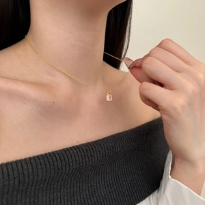 Nahaufnahme einer Dame mit Goldkette und quadratischem rosa Zirkon-Anhänger