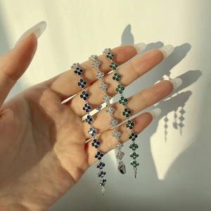 Macro detail of S925 silver bracelets with blue, white, and green clover zircon charms