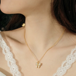 Close-up of a gold butterfly necklace with zircon micro-pave setting on lace dress