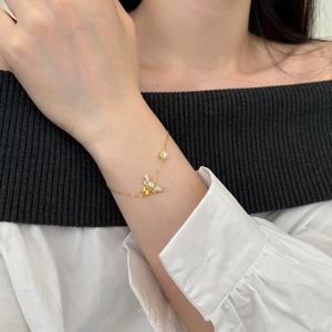 Detailed shot of a gold bee bracelet with yellow gemstones and white crystals on a wrist