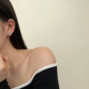 Macro detail of silver feather ear climber earrings with cubic zirconia stones on model