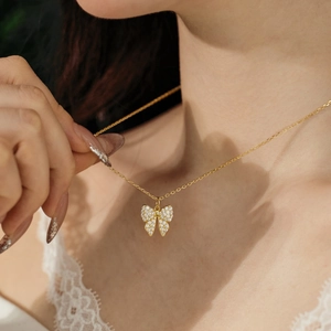 Close-up of a gold butterfly necklace with pave zircon stones worn by a model