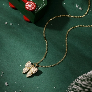 Detailed view of a gold-toned bowknot necklace with sparkling zircons on festive background