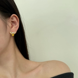 Detailed view of gold firefly stud earrings with sparkling zircon and yellow gem