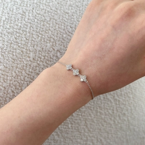 Detailed view of silver flower bracelet with three zircon-encrusted petal charms