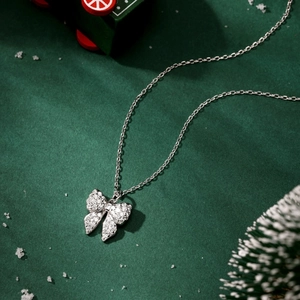 Macro shot of silver bow pendant with shimmering zircons on festive green background