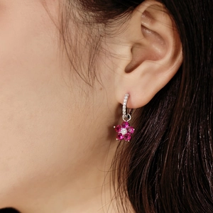 Détails macro des boucles d'oreilles fleur en argent avec pierres roses sur modèle