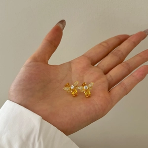 Close-up of gold-plated firefly earrings with sparkling cubic zirconia and yellow drop stone