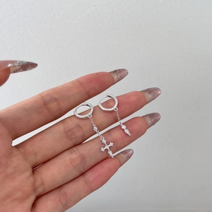Detail of S925 sterling silver hoop earrings with hanging cross and diamond accents