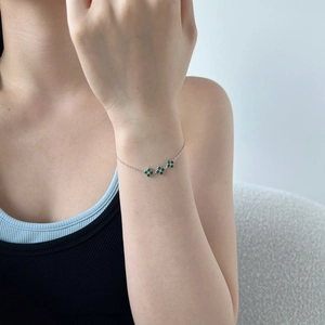 Close-up of S925 silver bracelet with green malachite clover charms on a model wrist