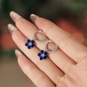 Détail macro de boucles d'oreilles en argent fleur de prunier et pierres bleues