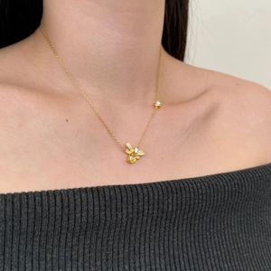Detail of a gold firefly pendant necklace with sparkling zircons worn by a model