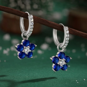 Vue détaillée de boucles d'oreilles fleur avec pétales bleus et pierres blanches