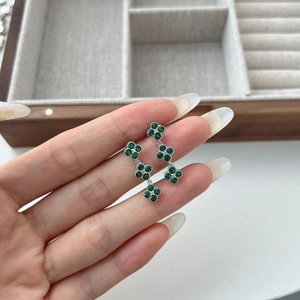 Detail of silver clover earrings with inlaid green zircon on jewelry box