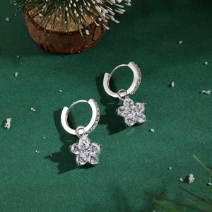 Détail de créoles en argent 925 avec breloques fleurs serties de zircons sur velours vert