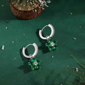 Gros plan de boucles d'oreilles en argent S925 avec pierres vertes sur fond hivernal