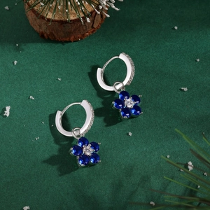 Détail de boucles d'oreilles fleur en argent 925 avec pétales bleus en décor festif