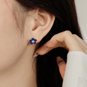 Gros plan de boucles d'oreilles en argent S925 avec pétales bleus et un diamant central