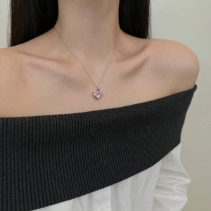 Detail view of a S925 silver necklace with pink heart pendant worn on a female model