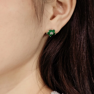 Détail du clou d'oreille fleur avec pierres vert émeraude et monture argentée sur l'oreille