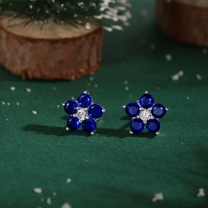 Détail macro de boucles d'oreilles fleur de prunier avec gemmes bleues et cristaux blancs