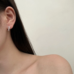 Close-up of S925 sterling silver studs with three heart-shaped zircons on model ear