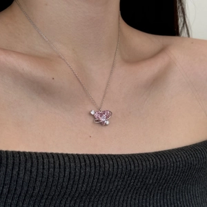 Primo piano di un ciondolo a pianeta cuore rosa con anello d'argento sulla catena